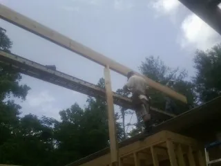Carpenter setting a ridge beam over a new addition frame — Ice Dam Removal by Roofing Brothers in Braithwaite