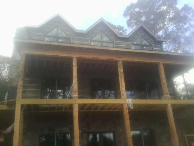 Dormers and porch framing on a large log home under construction — Roof Coating work by our crew in Braithwaite