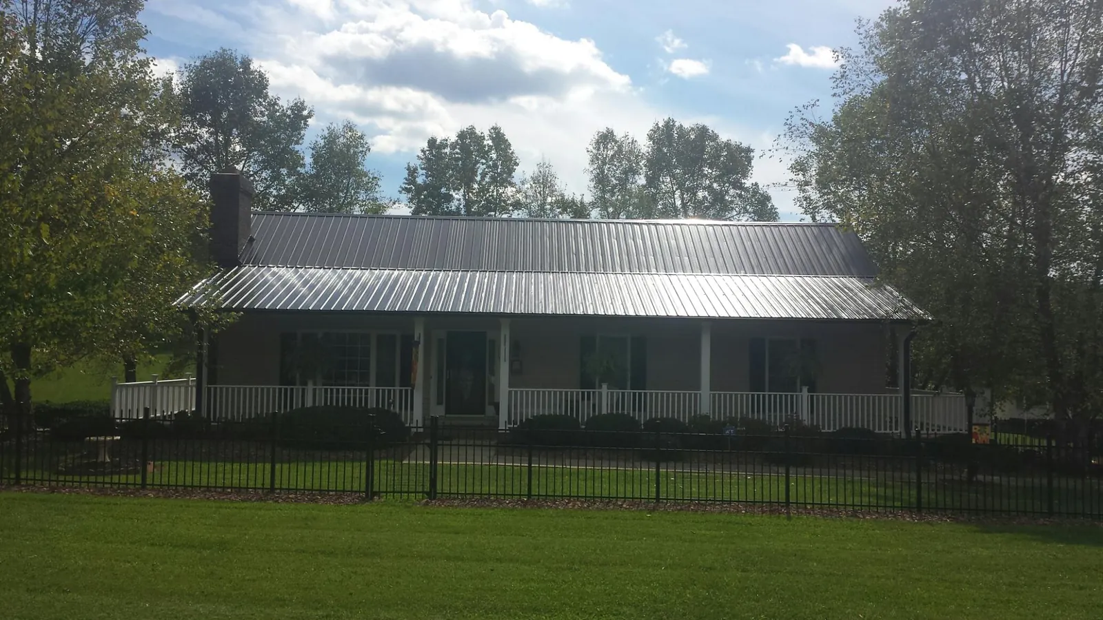 Gray metal roof on a brick ranch with a full width front porch — Gutter Guard Installation work by our crew in Braithwaite