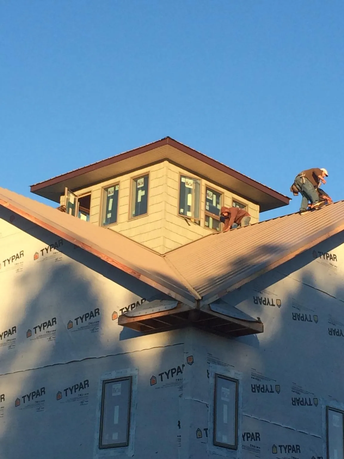 Roofers working around a rooftop cupola on a new metal roof at sunset — Roof Waterproofing in Braithwaite by Roofing Brothers